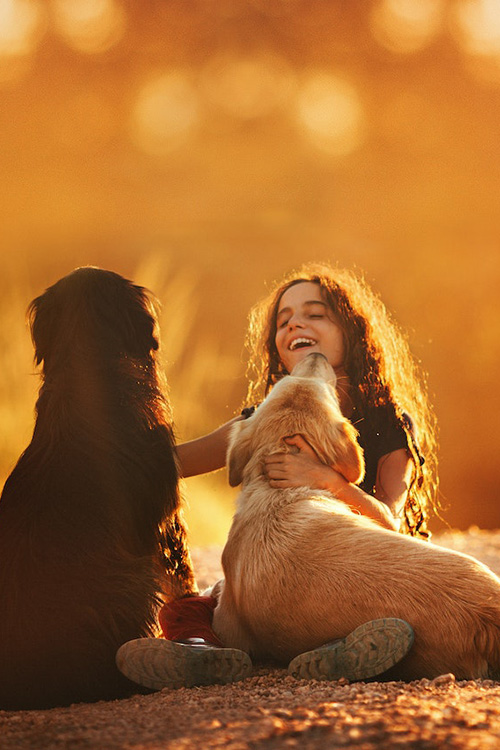 Young girl smiling while spending time with her 2 dogs